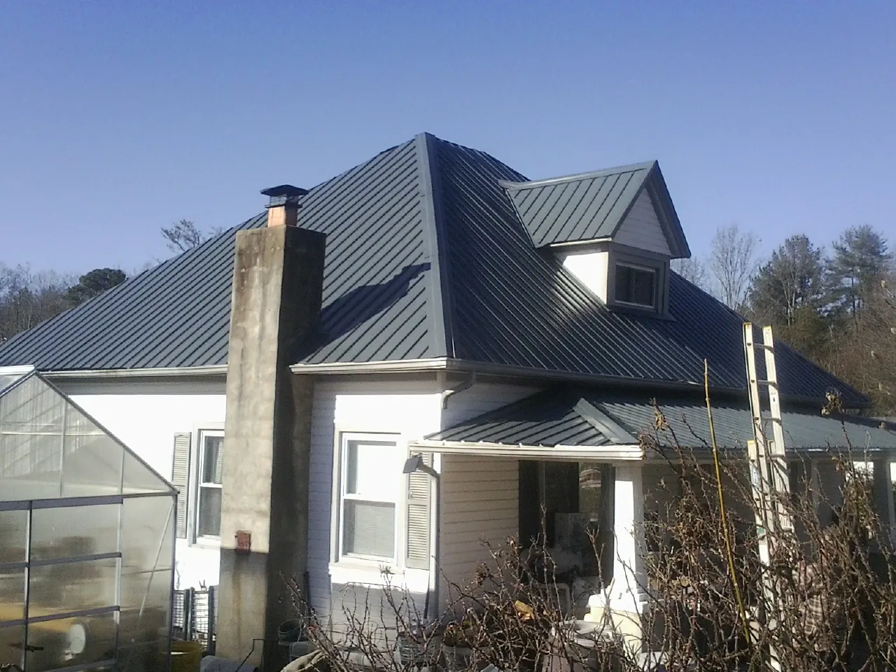 Dark blue standing seam metal roof on a white farmhouse with dormer — Slate & Tile Roof Repair by Roofing Brothers in Cedar Grove