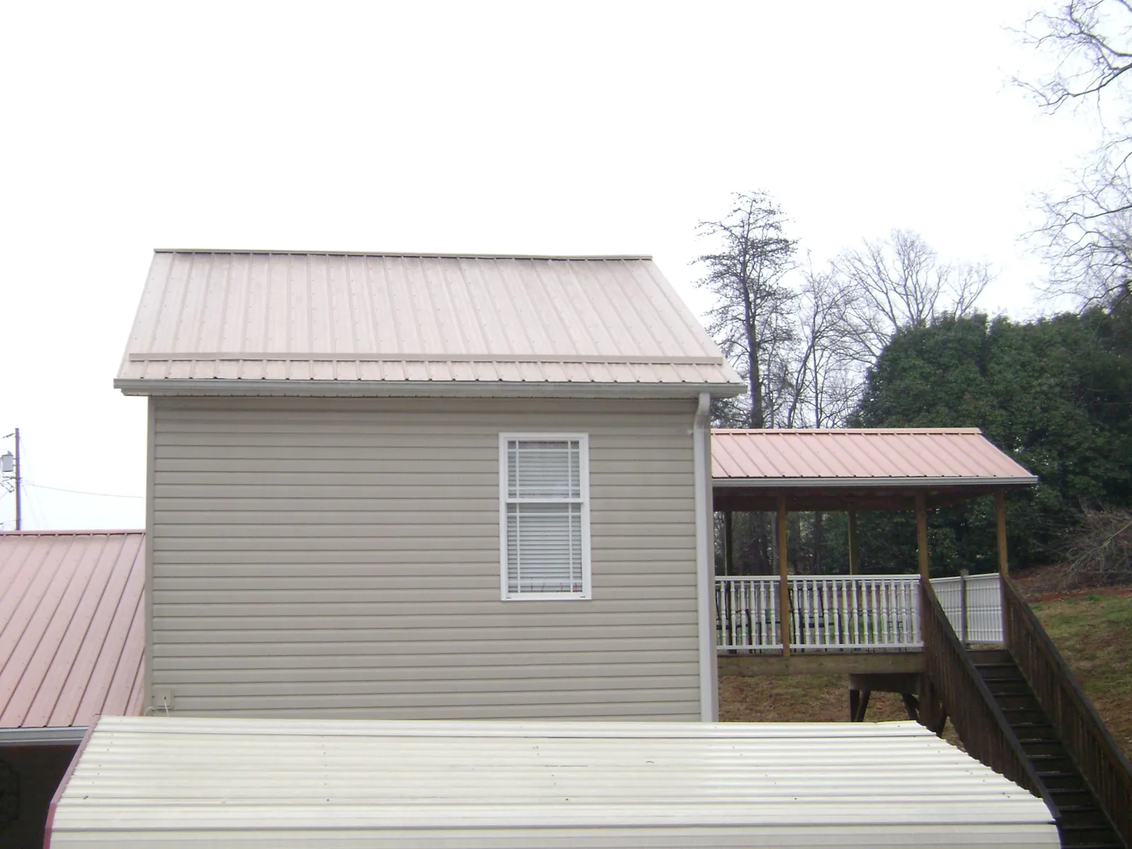 Tan metal roofs on a two story addition and attached porch, from a Roof Replacement job in Cedar Grove
