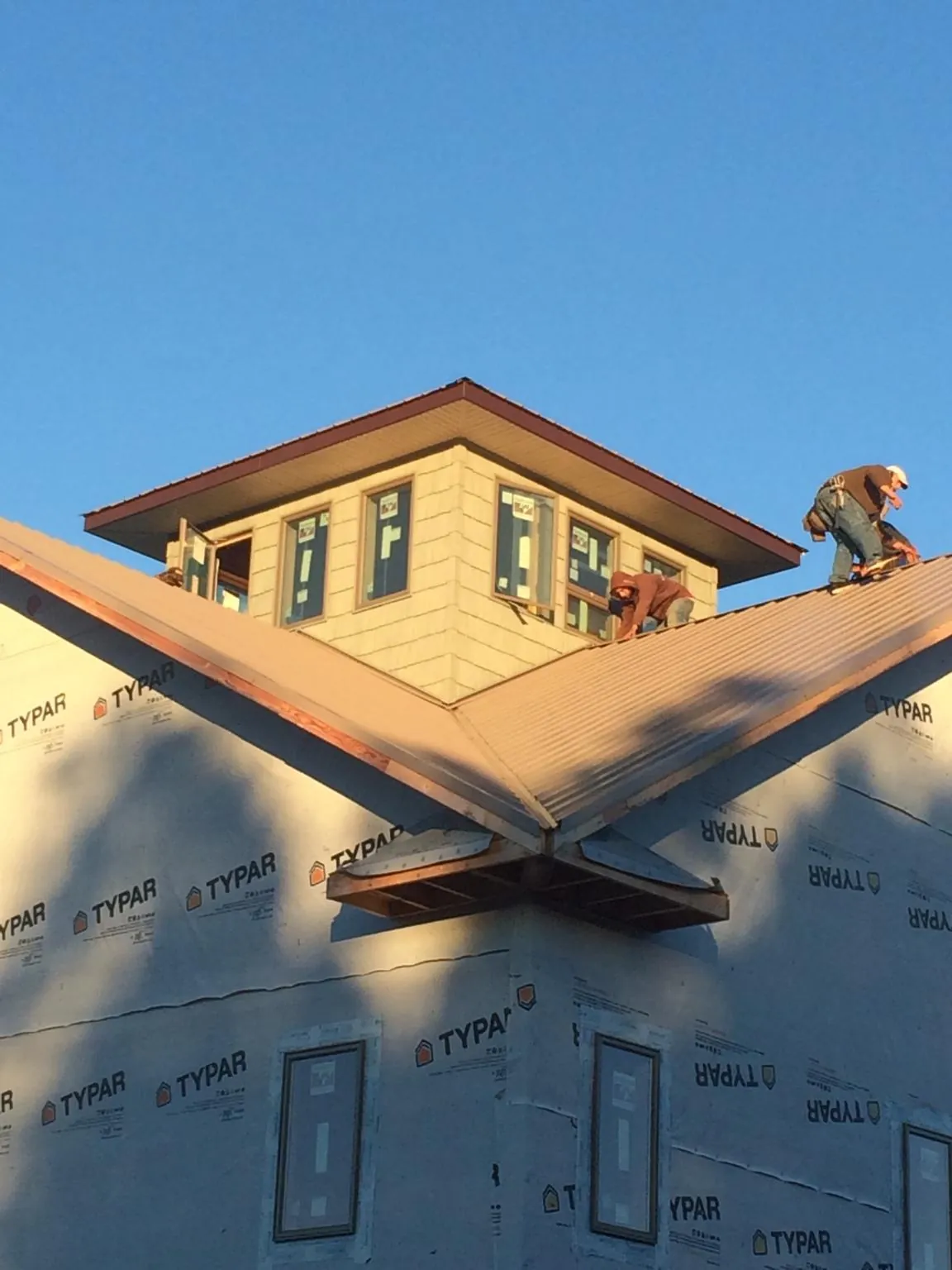 Roofers working around a rooftop cupola on a new metal roof at sunset — Roof Waterproofing in Cedar Grove by Roofing Brothers